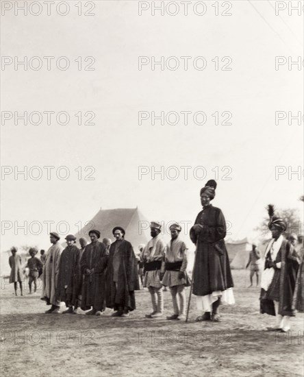 Kashmir Giant' at the Coronation Durbar, 1903. An unusually tall Indian man, described by an original caption as the 'Kashmir Giant', stands in line with several Indian dignitaries or aides at the Coronation Durbar camp. The caption comments that he measures "seven feet and eight inches" in height. Delhi, India, circa 1 January 1903. Delhi, Delhi, India, Southern Asia, Asia.