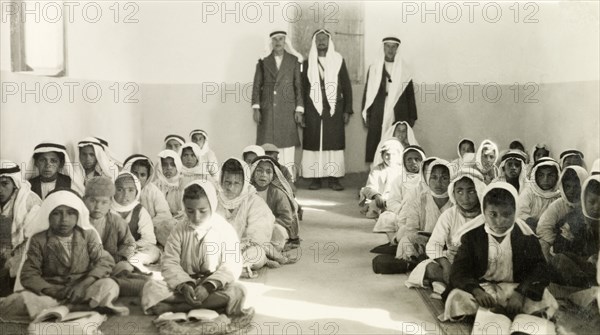School of Sheikhs Hassan al Ifranji and Abid'. Palestinian Arab schoolchildren wearing 'keffiyehs' (headdress) are supervised by three teachers as they sit cross-legged on a classroom floor studying from books. An original caption identifies this as the ?School of Sheikhs Hassan al Ifranji and Abid?, and makes reference to "Baha", perhaps meaning the Baha'i religion. British Mandate of Palestine (Israel), circa 1944. Israel, Middle East, Asia.