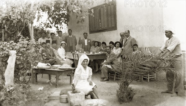 Lunch at Beit Hanoun. A group of friends pose for a portrait as they enjoy lunch together outdoors. Beit Hanoun, British Mandate of Palestine (Gaza Strip, Middle East), 1944. Beit Hanoun, Gaza Strip, Gaza Strip (Palestine), Middle East, Asia.
