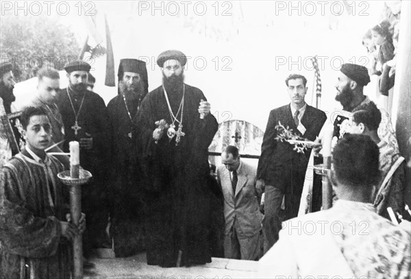 Priests at the Coptic Convent in Jaffa. Several Coptic priests take part in a ceremony at the Coptic Convent in Jaffa, wearing black floor-length robes and heavy, ornate crosses. Behind them, at the bottom of the steps, is William Ryder McGeagh, District Commissioner in Jerusalem. Jaffa, British Mandate of Palestine (Israel), April 1947. Jaffa, Tel Aviv, Israel, Middle East, Asia.