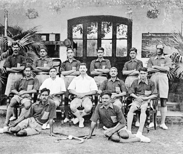 A hockey team at the Police Training School. W M Wright, probationary assistant superintendent, with No 1 Platoon hockey team of the Police Training School at Moradabad. Dressed in uniform, they pose for the camera beside a pair of crossed hockey sticks and a ball. Moradabad, United Provinces (Uttar Pradesh), India, 1934. Moradabad, Uttar Pradesh, India, Southern Asia, Asia.
