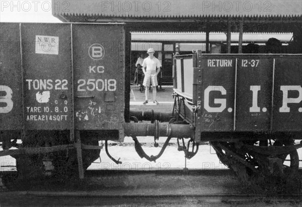 George Boon at Meerut railway station. Portrait of George Boon, an officer of the Indian Police, captured on the platform at Meerut railway station between two stationary freight carriages. Meerut, United Provinces (Uttar Pradesh), India, May 1935. Meerut, Uttar Pradesh, India, Southern Asia, Asia.