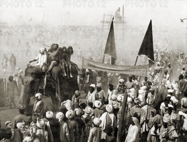 Procession at the Ardh Kumbh Mela. A procession containing elephants and banners passes through crowds of Hindu pilgrims on its way to the Triveni Sangam (the holy confluence of the Yamuna, Saraswati and Ganges Rivers) at the Ardh Kumbh Mela. Allahabad, United Provinces (Uttar Pradesh), India, January 1936. Allahabad, Uttar Pradesh, India, Southern Asia, Asia.