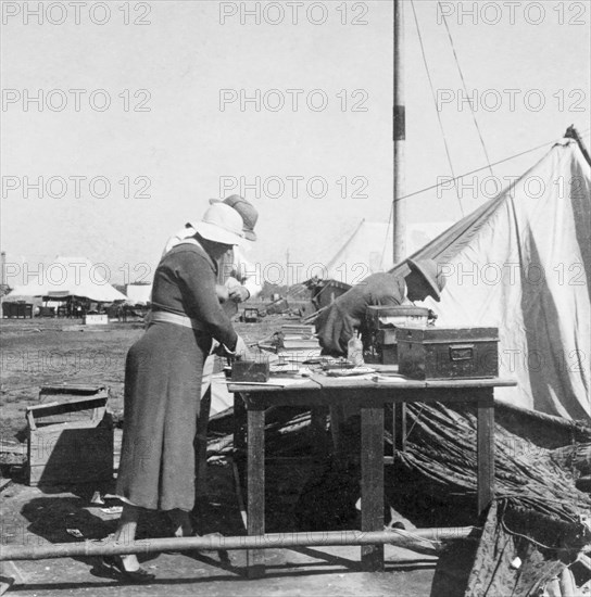 Salvaging books after a storm. A European couple salvage books and papers after a heavy storm at camp of James Ferguson, Indian Police. United Provinces (Uttar Pradesh), India, 1936., Uttar Pradesh, India, Southern Asia, Asia.