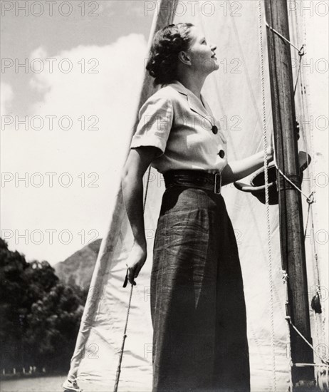 Yachting on Naini Tal Lake. A young woman stands on the deck of a yacht on Naini Tal Lake, dressed in typical 1930s style with high-waisted trousers and waved, shoulder-length hair. Naini Tal, India, 1937. Naini Tal, Uttaranchal, India, Southern Asia, Asia.
