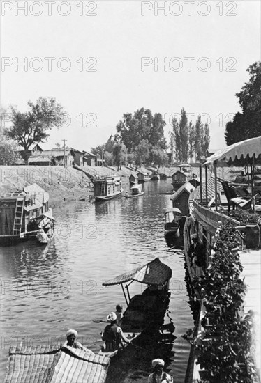 Shikaras on a Srinagar canal. Several shikaras (houseboats) are moored along the banks of a Srinagar canal. Srinagar, Jammu and Kashmir, India, 1934. Srinagar, Jammu and Kashmir, India, Southern Asia, Asia.