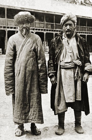 Kashmiri men from Srinagar. Full-length portrait of two Kashmiri men from Srinagar, dressed in heavy outer garments and turbans with padded footwear. Srinagar, Jammu and Kashmir, India, 1934. Srinagar, Jammu and Kashmir, India, Southern Asia, Asia.