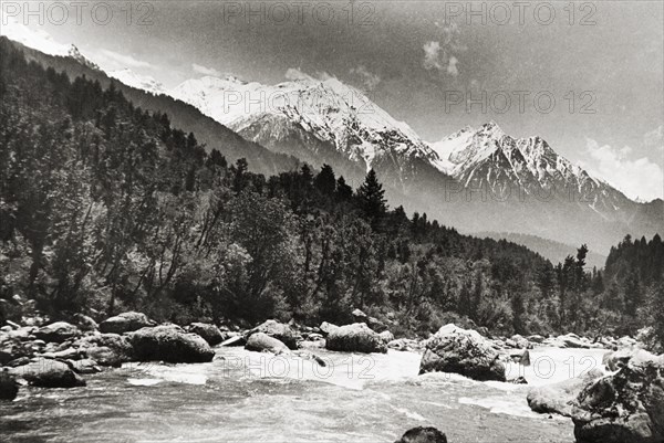 Sheshnag Mountain from the Pahalgam Valley. The snow-capped peaks of Sheshnag Mountain rise up behind the Liddar River as it cascades through the densely forested Pahalgam Valley. Near Pahalgam, Jammu and Kashmir, India, 1934., Jammu and Kashmir, India, Southern Asia, Asia.