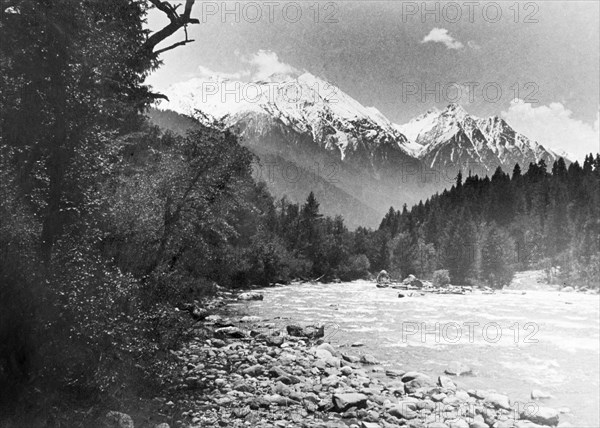 Sheshnag Mountain from the Pahalgam Valley. The snow-capped peaks of Sheshnag Mountain rise up behind the Liddar River as it cascades through the densely forested Pahalgam Valley. Near Pahalgam, Jammu and Kashmir, India, 1934., Jammu and Kashmir, India, Southern Asia, Asia.