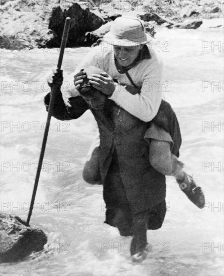 Crossing a Kashmiri Stream'. A Kashmiri trek porter carries a George Boon on his back as he negotiates a fast-flowing mountain stream near Sekwas Pass. Kashmir, India, June 1934., Jammu and Kashmir, India, Southern Asia, Asia.