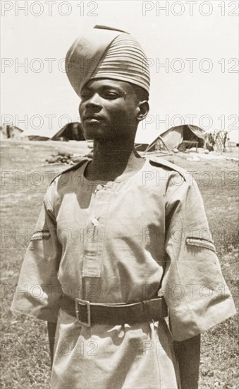 Portrait of an Arab 'onbashi'. An Arab 'onbashi' (corporal) stands to attention, wearing military uniform and a 'pagari' (turban). His exact regiment is unknown, but related information suggests he belongs to either the Somaliland Scouts, the Sudan Defence Force or, perhaps most likely, the Aden Protectorate Levies. Possibly Aden, Yemen, circa 1957. Aden, Adan, Yemen, Middle East, Asia.