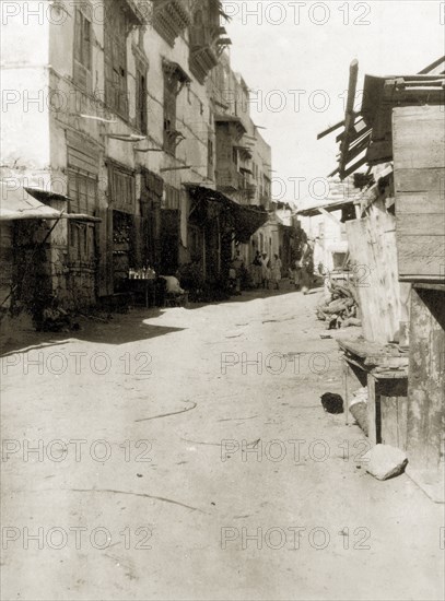 A back street in Suakin. A back street of Suakin. Several of the buildings on the left display decorative bay or oriel windows and appear to be somewhat dilapidated. Suakin, Sudan, circa 1925. Suakin, Red Sea, Sudan, Eastern Africa, Africa.