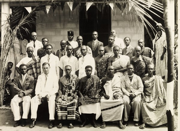 Celebrating VE Day at Mampong. Nana Kobina WIafe II, Chief of Mampong, and Alan Bullwinkle, District Commissioner of Obuasi, pose for a group portrait with Asante (Ashanti) elders and dignitaries during celebrations for VE Day. Mampong, Asante, Gold Coast (Ghana), 1945. Mampong, Ashanti, Ghana, Western Africa, Africa.