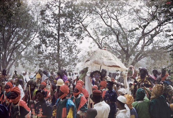 The Emir of Kano in a Sallah parade. The new Emir of Kano, Alhaji Ado Bayero, rides to the Residency beneath a ceremonial umbrella during a colourful procession for Sallah, an Islamic celebration held to mark the end of Ramadan. Kano, Nigeria, 1963. Kano, Kano, Nigeria, Western Africa, Africa.