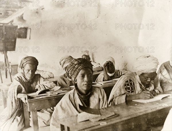 Adult Hausa students in a classroom, Kano. Adult Hausa pupils sit studying at benches in a Nigerian classroom. Probably Kano, Nigeria, circa 1915. Kano, Kano, Nigeria, Western Africa, Africa.
