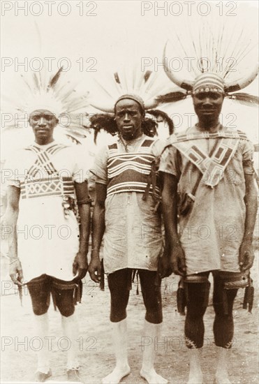 Three Zulu rickshaw pullers. Portrait of three Zulu rickshaw pullers. They wear distinctive headgear made from animal horns and feathers, and are decorated with white body paint on their feet and lower legs. Durban, Natal (KwaZulu-Natal), South Africa, 1918. Durban, KwaZulu Natal, South Africa, Southern Africa, Africa.