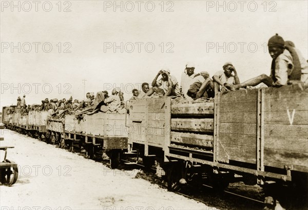 African schutztruppes travel by rail. African schutztruppes travel in crowded, open railway wagons on a train journey through German East Africa. German East Africa (Tanzania), circa 1910. Tanzania, Eastern Africa, Africa.