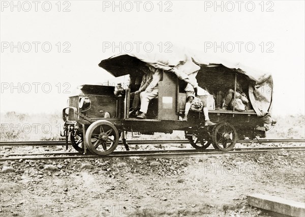 A truck converted to run on rails. Several European men travel in the cab and coach of a truck modified to run on rails. German East Africa (Tanzania), circa 1910. Tanzania, Eastern Africa, Africa.