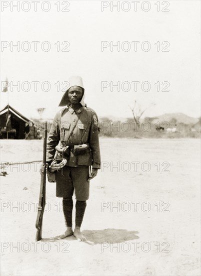 An askari of the King's African Rifles. Portrait of an armed askari (soldier) of the King's African Rifles, dressed in full military uniform. Eastern Africa, circa 1910., Eastern Africa, Africa.