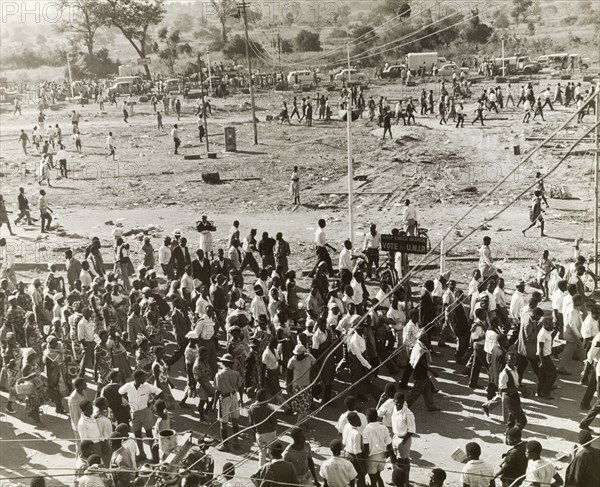 UNIP supporters at an electioneering rally. United National Independence Party (UNIP) supporters disperse following an electioneering rally held two months before Zambian independence. UNIP won the Zambian election of January 1964, but their authority was challenged by Alice Lenshina's Lumpa Church. Violent conflict ensued and in summer 1964, UNIP activists attacked the village of Peshuku, reportedly killing 46 people. Peshuku, Eastern Province, Northern Rhodesia (Zambia), August 1964. Peshuku, East (Zambia), Zambia, Southern Africa, Africa.