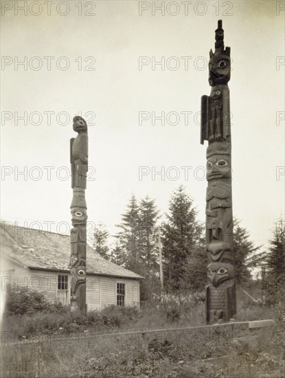 Tlingit totem poles, Alaska. Two Native American totem poles stand outside Chief Shakes Tribal House, a traditional, high-caste Tlingit house on Chief Shakes Island in Wrangell Harbour. Wrangell, Alaska, United States of America, circa 1931. Wrangell, Alaska, United States of America, North America, North America .