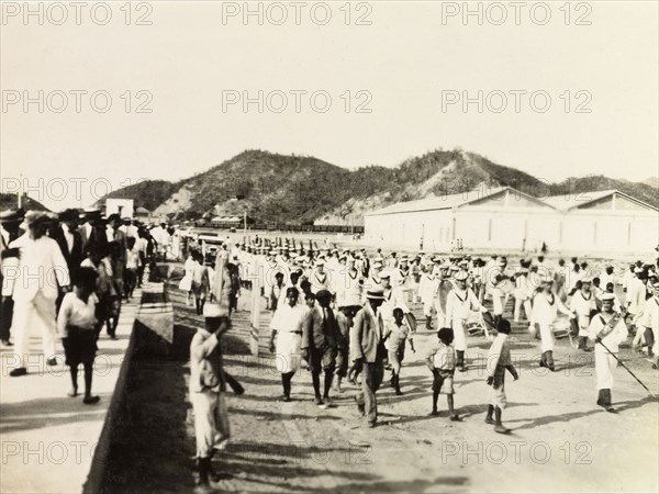 Royal Navy parade, Trinidad. British Royal Navy sailors from HMS Dauntless parade along a street in Siparia, accompanied by a military band. A crowd of Trinidadian spectators gather to watch the procession. Siparia, Trinidad, circa 1931. Siparia, Trinidad and Tobago, Trinidad and Tobago, Caribbean, North America .