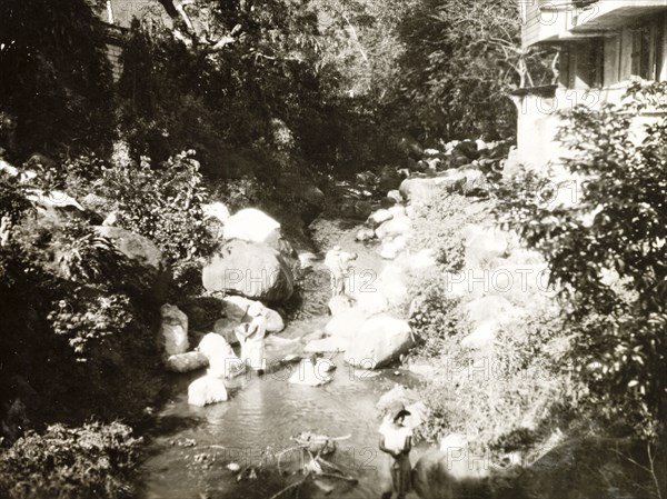 Washing clothes at a plantation house. Workers at a coffee plantation wash their clothes in a shallow stream beside a plantation house. Probably Costa Rica, circa 1931. Costa Rica, Central America, North America .