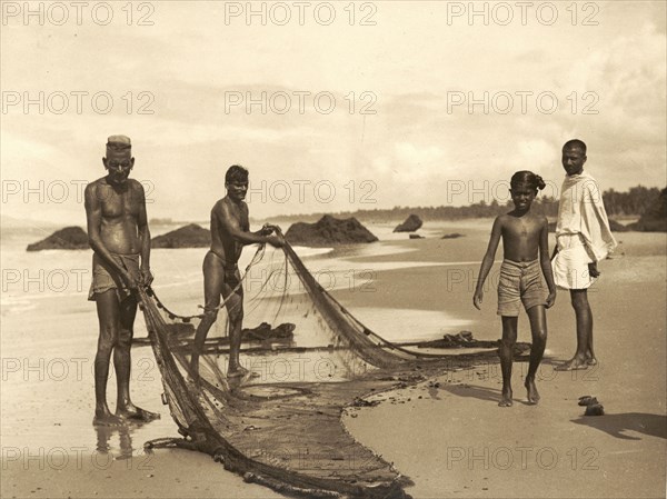 Fishermen on Azhikkal beach. Fishermen prepare their nets on a wide sandy beach. Azhikkal, Kerala, India, circa 1936. Azhikkal, Kerala, India, Southern Asia, Asia.