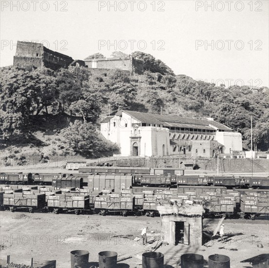 Rail sidings at Mormugao port. Empty freight cars sit on sidings beneath a prominent fortress at Mormugao docks. Mormugao, Goa, India, circa 1937. Mormugao, Goa, India, Southern Asia, Asia.