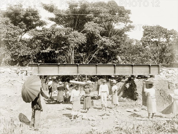 Flood works beneath a railway bridge, Trinidad. Female labourers clear rubble from beneath a railway bridge, opening up an eight-metre water channel to prevent flooding on a nearby extension line of the Trinidad Government Railway. Caroni, Trinidad, circa 1912. Caroni, Trinidad and Tobago, Trinidad and Tobago, Caribbean, North America .