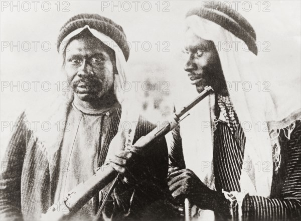 Armed Arab dissidents. Portrait of two men dressed in typical Arab attire and armed with rifles. An original caption identifies the men as ?rioters?, probably a reference to their status as Palestinian Arab dissidents of the Great Uprising (1936-39). Jaffa, British Mandate of Palestine (Israel), circa 1938. Jaffa, Tel Aviv, Israel, Middle East, Asia.