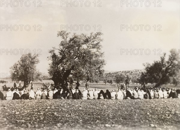 Police questioning Palestinian Arabs, 1938. A long line of Palestinian Arab villagers sit on the ground, awaiting questioning from the Palestine Police Force. During the period of the Great Uprising (1936-39), an additional 20,000 British troops were deployed to Palestine in an attempt to clamp down on Arab dissidence. British Mandate of Palestine (Middle East), 1938., Middle East, Asia.