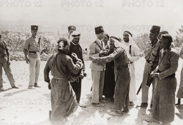 Police questioning Palestinian Arabs, 1938. Armed officers of the Palestine Police Force question a group of Palestinian Arab men from a rural village. During the period of the Great Uprising (1936-39), an additional 20,000 British troops were deployed to Palestine in an attempt to clamp down on Arab dissidence. British Mandate of Palestine (Middle East), 1938., Middle East, Asia.