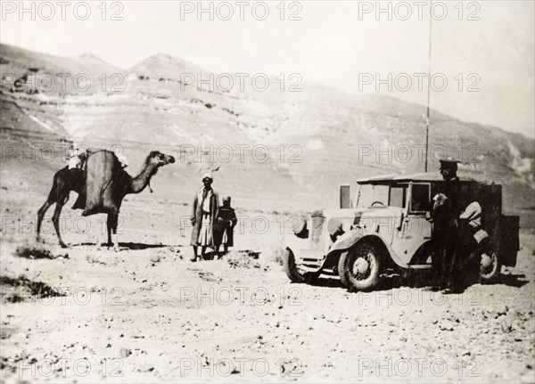 Signaller in the Palestinian desert. A British officer of the Royal Corps of Signals stops his car on a desert road beside an Arab man and a boy travelling with a camel. During the period of the Great Uprising (1936-39), an additional 20,000 British troops were deployed to Palestine in an attempt to clamp down on Arab dissidence. British Mandate of Palestine (Middle East), circa 1938., Middle East, Asia.