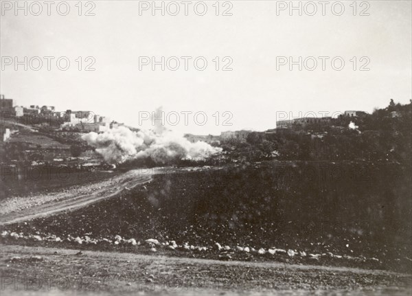 Demolition of a Palestinian house. A cloud of dust engulfs a residential area in Nablus following the demolition of a Palestinian house, a measure taken by British forces to clamp down on Arab dissidence during the Great Uprising (1936-39). Nablus, British Mandate of Palestine (West Bank, Middle East), circa 1938. Nablus, West Bank, West Bank (Palestine), Middle East, Asia.