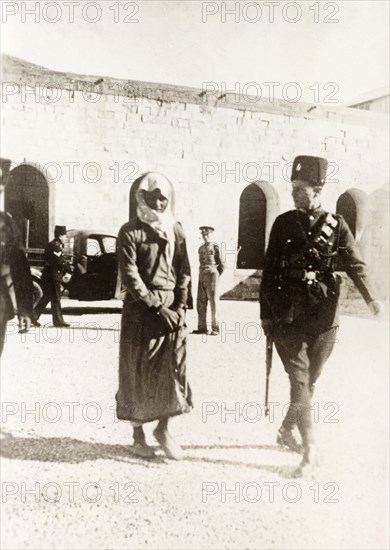 Arab prisoner led to court martial. A British police officer escorts a young Arab prisoner to court martial, where he was tried and sentenced to death for committing rebel acts during the Great Uprising (1936-39). British Mandate of Palestine (Middle East), circa 1938., Middle East, Asia.