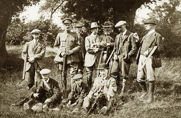 Shooting party at Hardwick Estate. A group of men and a young boy pose for a portrait with rifles and gun dogs whilst hunting at Hardwick Estate. Derbyshire, England, circa 1918., Derbyshire, England (United Kingdom), Western Europe, Europe .