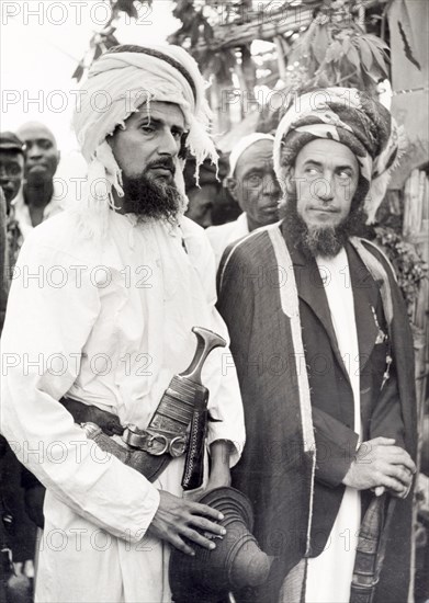 Two Arab men in Dar es Salaam. Official publicity shot for the Tanganyikan government of two Arab men dressed in traditional robes with turbans. The man nearest to the camera carries a curved dagger with a decorative sheath. Probably Dar es Salaam, Tanganyika Territory (Tanzania), circa 1960. Dar es Salaam, Dar es Salaam, Tanzania, Eastern Africa, Africa.