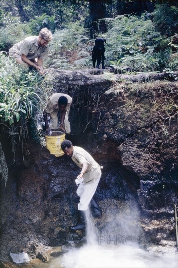 Adding lime to neutralise the water. District Forest Officer James Lang Brown (top) watches as two Ugandan Forest Rangers add lime to a forest nursery reservoir in order to neutralise the acidity of the water. Bugamba, South West Uganda, September 1963., West (Uganda), Uganda, Eastern Africa, Africa.