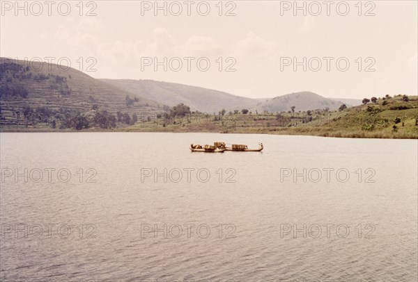 Dugout canoes on Lake Bunyonyi. Two dugout canoes filled with bamboo baskets float on the calm waters of Lake Bunyonyi near the Uganda-Rwanda border. Kigezi, South West Uganda, September 1963., West (Uganda), Uganda, Eastern Africa, Africa.