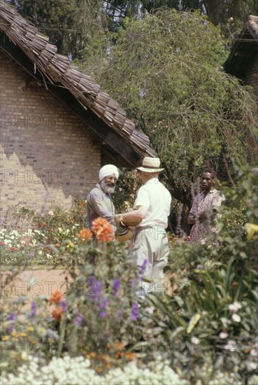 Making friends at the White Horse Inn. Alan, the father of District Forest Officer James Lang Brown, befriends an elderly Sikh man at the White Horse Inn in Kabale. A related caption comments: "The Sikhs filled a niche in East Africa, being expert craftsmen - carpenters, engineers and of course sawmillers and ginners. All of them charming, and some of them rogues". Kabale, West Uganda, July 1962. Kabale, West (Uganda), Uganda, Eastern Africa, Africa.