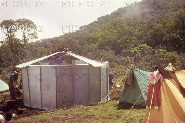 Erecting a 'uniport' on Mount Elgon. Members of an expedition erect a 'uniport' (rondavel) in sections on the upper slopes of Mount Elgon. The structure, made from prefabricated aluminium panels, was intended for use by the Uganda Mountain Club. East Uganda, 1962., East (Uganda), Uganda, Eastern Africa, Africa.