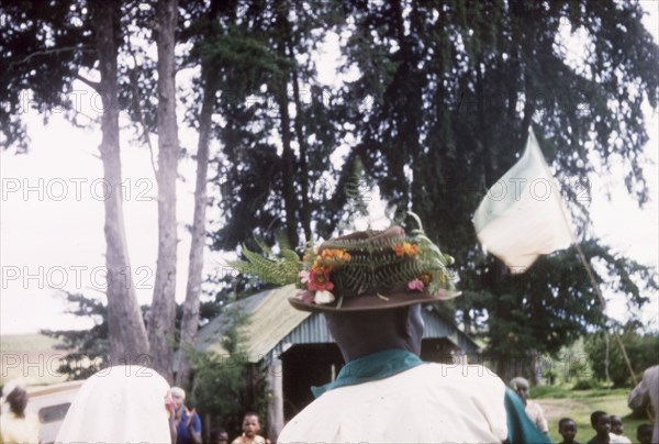 A Christmas hat. Seen from behind, an African man wears a trilby hat decorated with flowers and ferns during Christmas celebrations at the Afro-Israel Mission. Kapsimotwa, Kenya, December 1961., Rift Valley, Kenya, Eastern Africa, Africa.