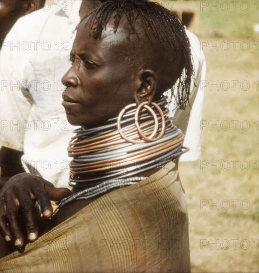 Portrait of a Pian woman. Close-up, profile shot of a Pian woman at the Nabilatuk County Show. A related caption comments that her numerous ?copper and aluminium neck rings denote considerable wealth?. Nabilatuk, North East Uganda, October 1959., East (Uganda), Uganda, Eastern Africa, Africa.