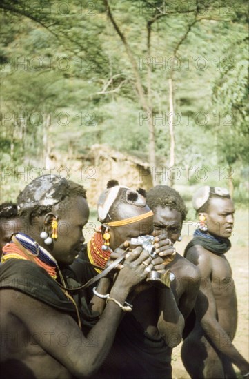 Henry Osmaston's Leica'. Suk (Pokot) porters working with a British forestry survey team experiment with a Leica camera belonging to Henry Osmaston (Working Plans Officer, Uganda Forest 
Department) on a safari to the Karasuk hills. Kenya, May 1959., East (Uganda), Uganda, Eastern Africa, Africa.