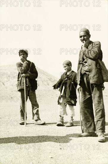 Portrait of an Afghan man and two boys. Dressed in tattered clothes, an Afghan man and two boys pose shyly for a portrait. Probably Eastern Afghanistan, 1942. Afghanistan, Central Eurasia, Asia.