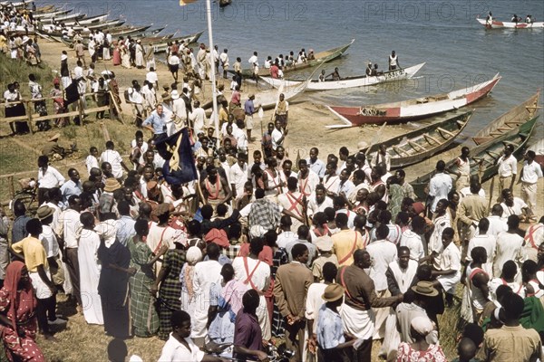 Regatta celebrating the Kabaka's return. Crowds gather on the banks of Lake Victoria to watch a band during a regatta celebrating the return from exile of Edward Mutesa II, Kabaka (King) of Buganda. Central Uganda, October 1955., Central (Uganda), Uganda, Eastern Africa, Africa.