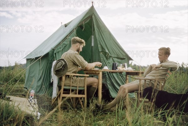 Breakfast on safari'. District Forest Officer James Lang Brown (left) enjoys breakfast with a colleague outside his tent during a safari to survey Kibale Forest. Toro, West Uganda, 1955., West (Uganda), Uganda, Eastern Africa, Africa.