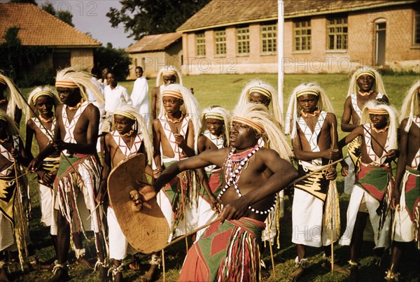 Banyaruanda dance in ceremonial dress. A group of Banyaruanda men and boys dance in ceremonial costume including headdresses and wraparound, tasselled skirts. Fort Portal, West Uganda, 1956., West (Uganda), Uganda, Eastern Africa, Africa.