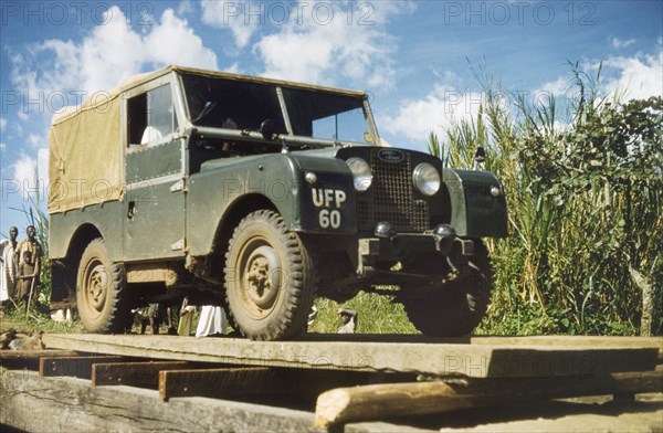James Lang Brown tests a bridge. District Forestry Officer James Lang Brown drives a Land Rover across a newly constructed bridge to test its strength. The bridge was built as part of a community development project, using timber and unpaid labour from the local community. Toro, West Uganda, June 1957., West (Uganda), Uganda, Eastern Africa, Africa.